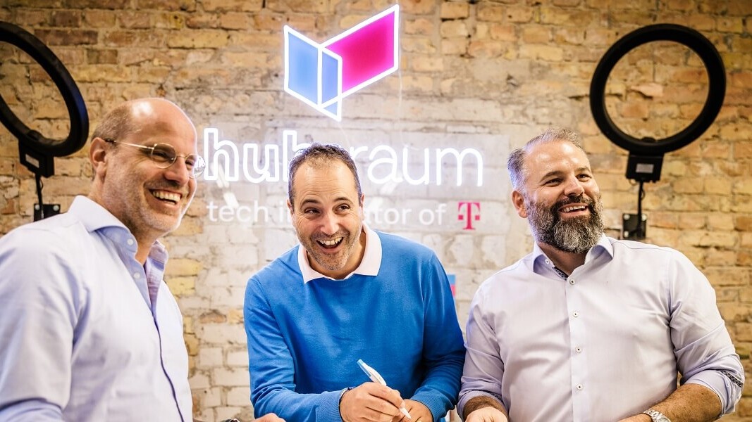 hubraum - tech incubator of Deutsche Telekom 3 men standing in front of a wall with hubraum logi and laughing